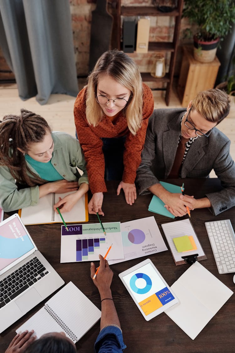 A Group Of People Discussing A Chart On A Table