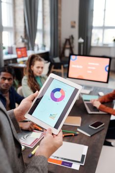 Colleagues reviewing business data on a tablet in a modern office setting.