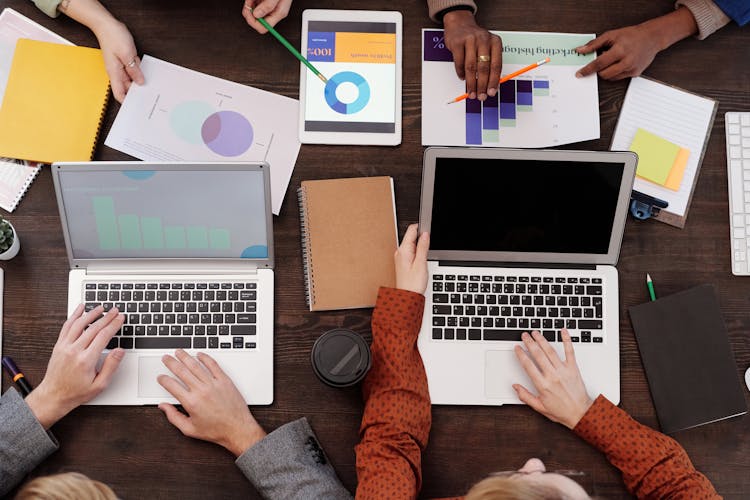 A Group Of People With Graphs And Pie Charts On Table