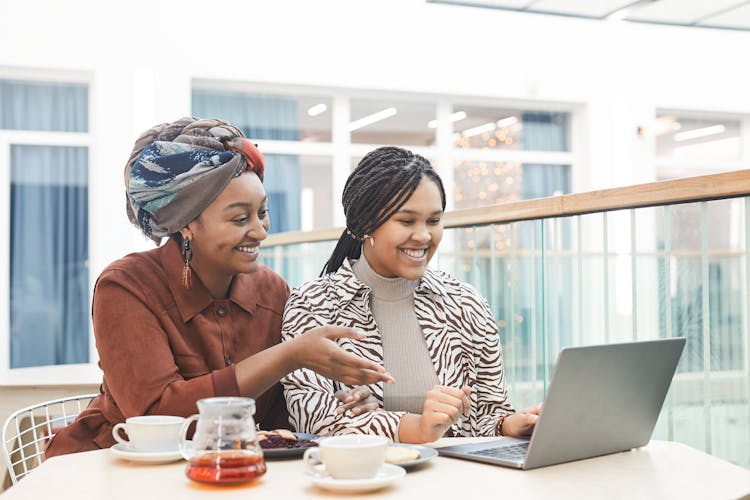 Women Using A Laptop While Having Tea