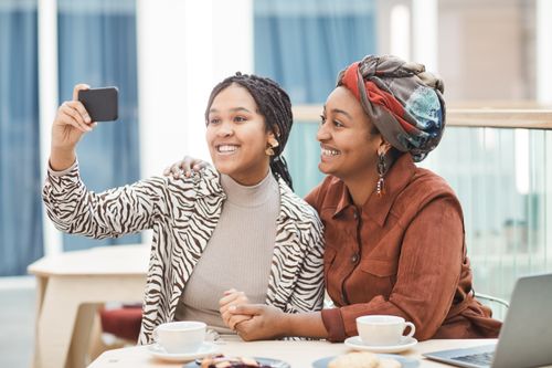 Free Two women enjoying a café moment, taking a selfie together, and sharing smiles. Stock Photo