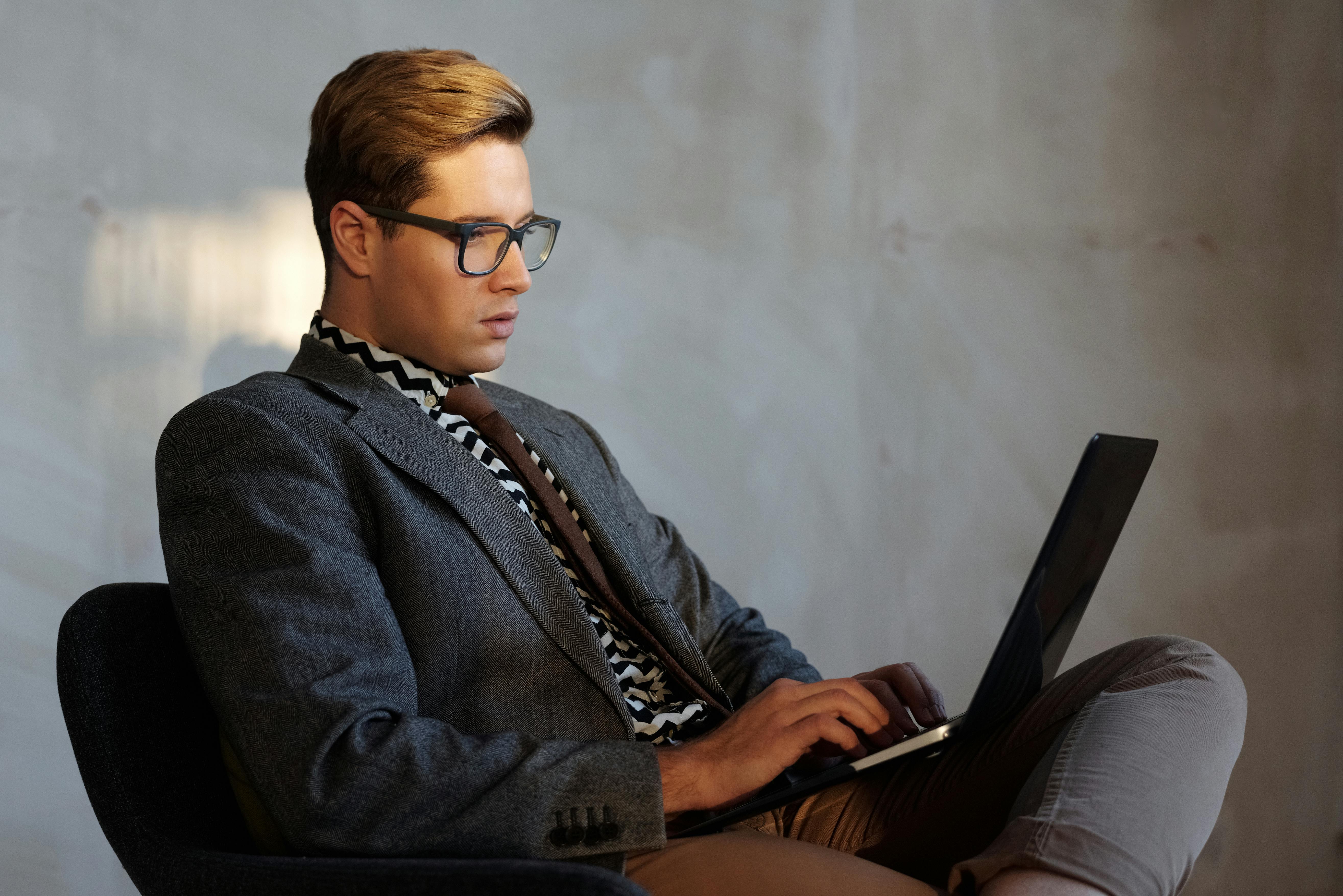 Stylish young man in modern office using laptop for work.