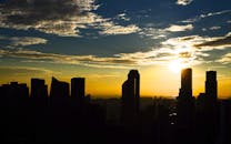 充满活力的金色日出天空和引人注目的云层映衬着城市摩天大楼的剪影