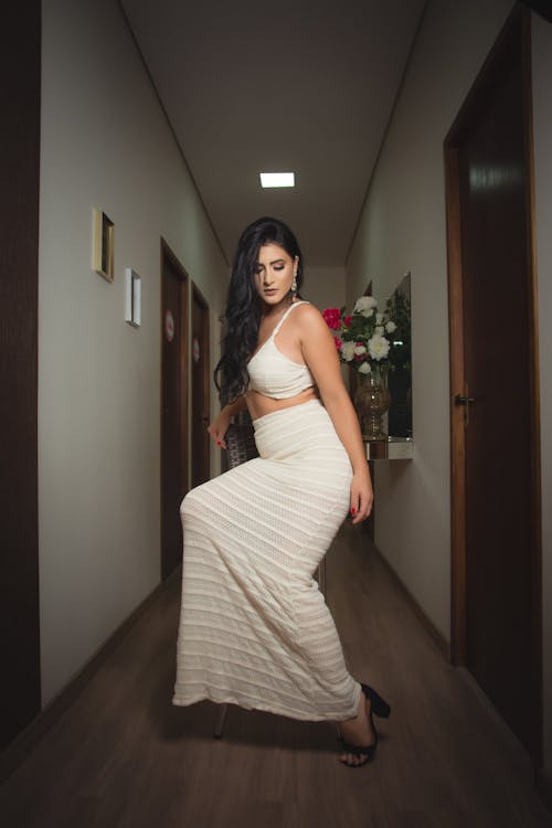 Woman in White Dress Standing Near Brown Wooden Door