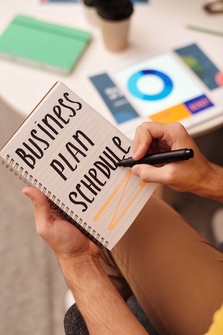 A Person Using A Marker Writing On A Notebook