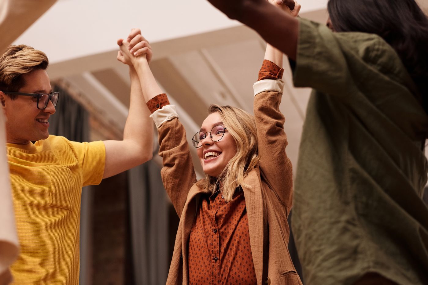 Colleagues cheering with hands raised at a team gathering — photo by Mikael Blomkvist on Pexels