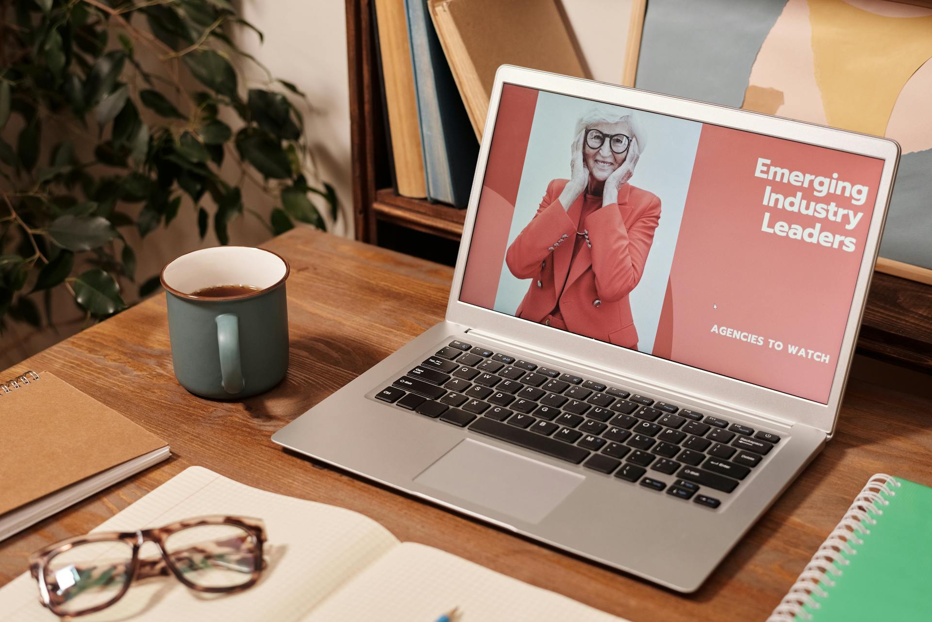 Cozy office desk with a laptop displaying 'Emerging Industry Leaders' and coffee mug.