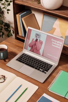 Stylish desk setup with a laptop, notebooks, and coffee mug, ideal for productivity.