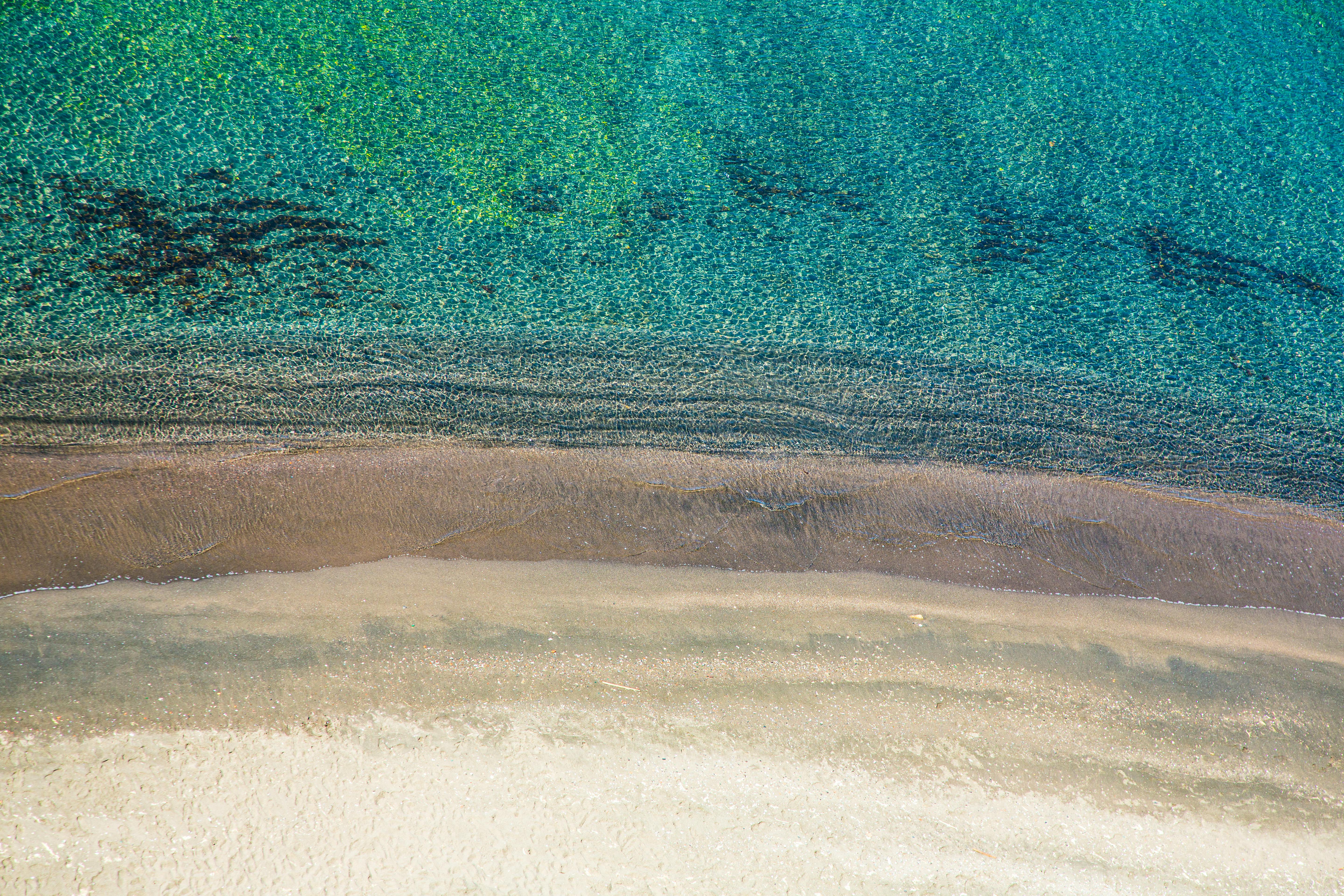 Sandy shore washed by turquoise water of ocean · Free Stock Photo