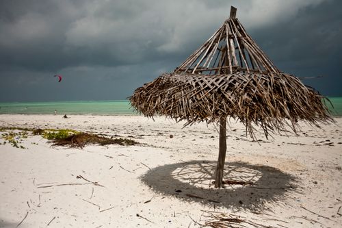 Free Timber umbrella ruined by wind on sandy coast of ocean under rainy cloudy sky Stock Photo