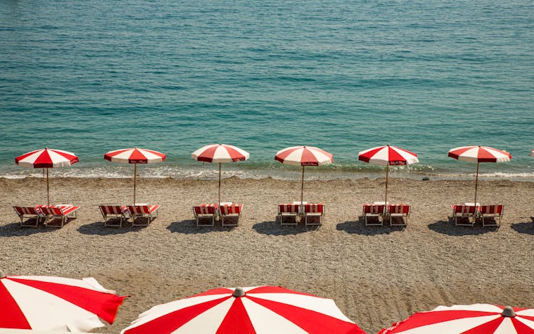 Rows Of Red And White Umbrellas On Clean Beach