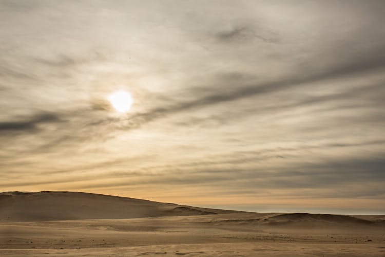 Sandy Desert Under Cloudy Sky With Bright Sun