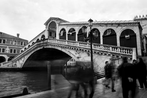 Grayscale Photo of People Walking Near the Bridge