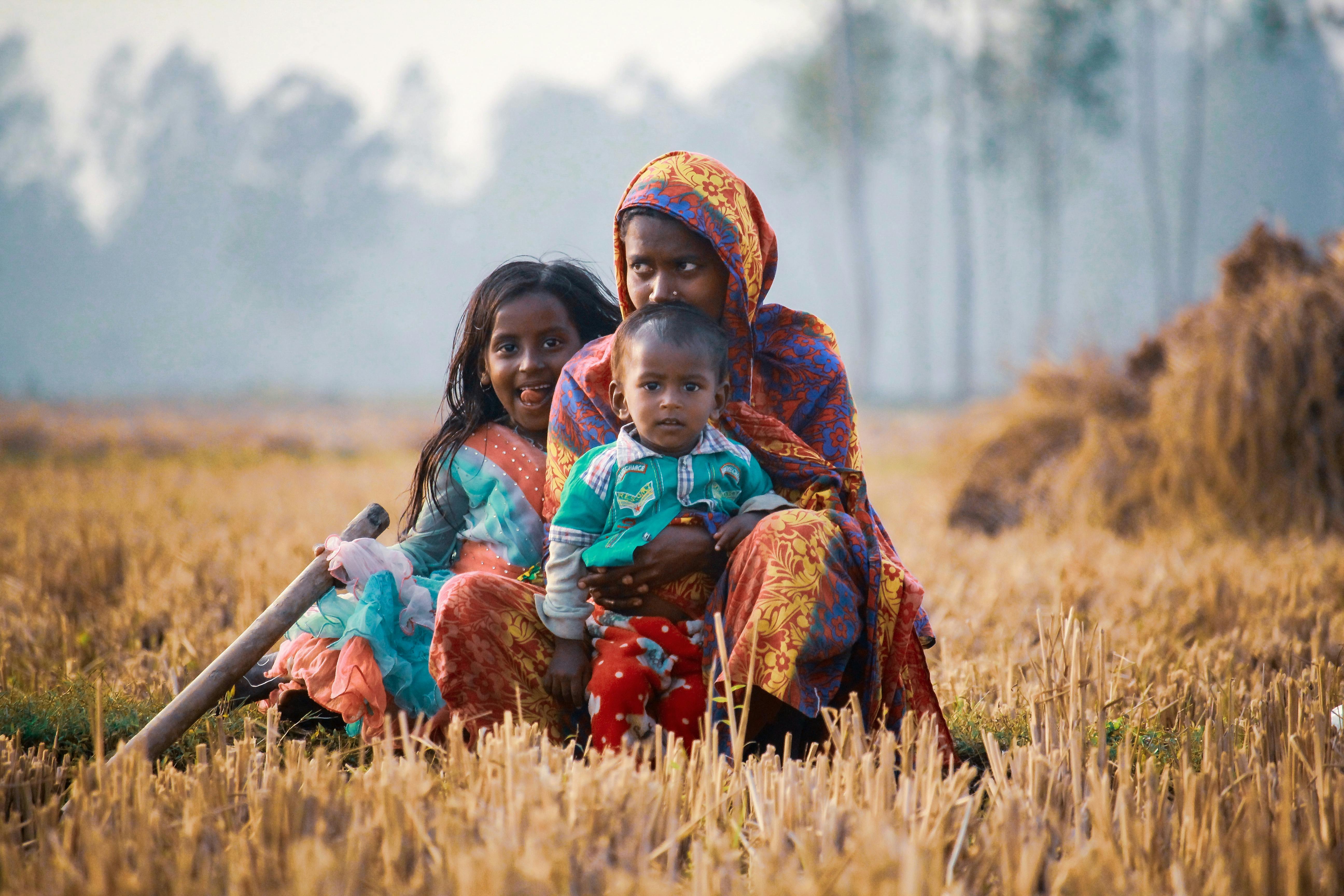 family sitting on brown grass field