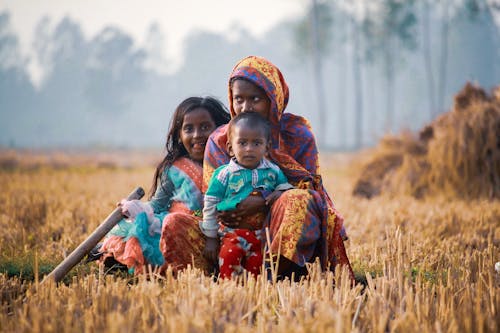 Family Sitting on Brown Grass Field