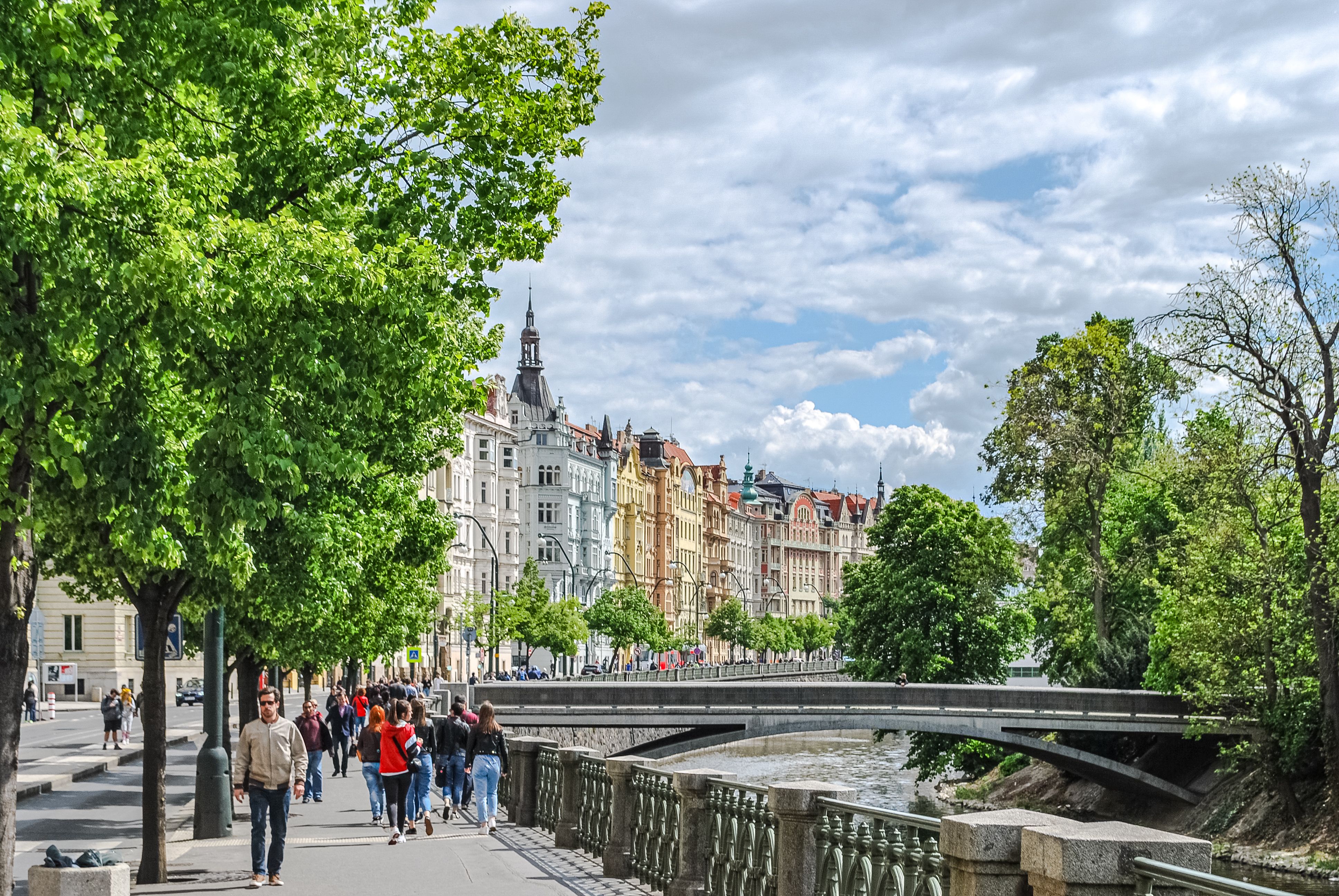 Explore the vibrant architecture and lively street scene along the river in Prague, Czech Republic.