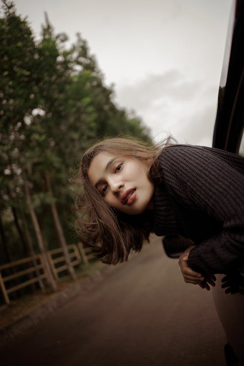 Woman leaning out of car driving on road