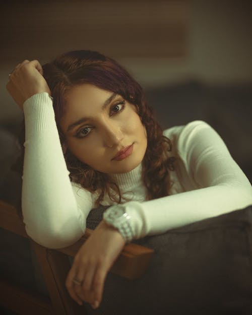 Free Woman in White Long Sleeve Shirt Lying on Brown Wooden Chair Stock Photo