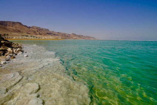 Explore the serene turquoise waters and salty shoreline of the Dead Sea on a sunny day.