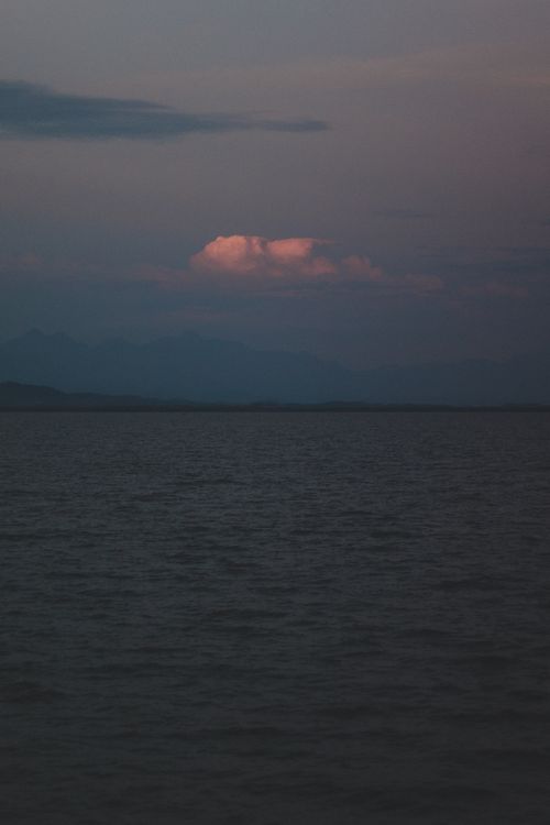 Free A serene sunset over the sea in Rio de Janeiro, Brazil, with vibrant cloud colors. Stock Photo