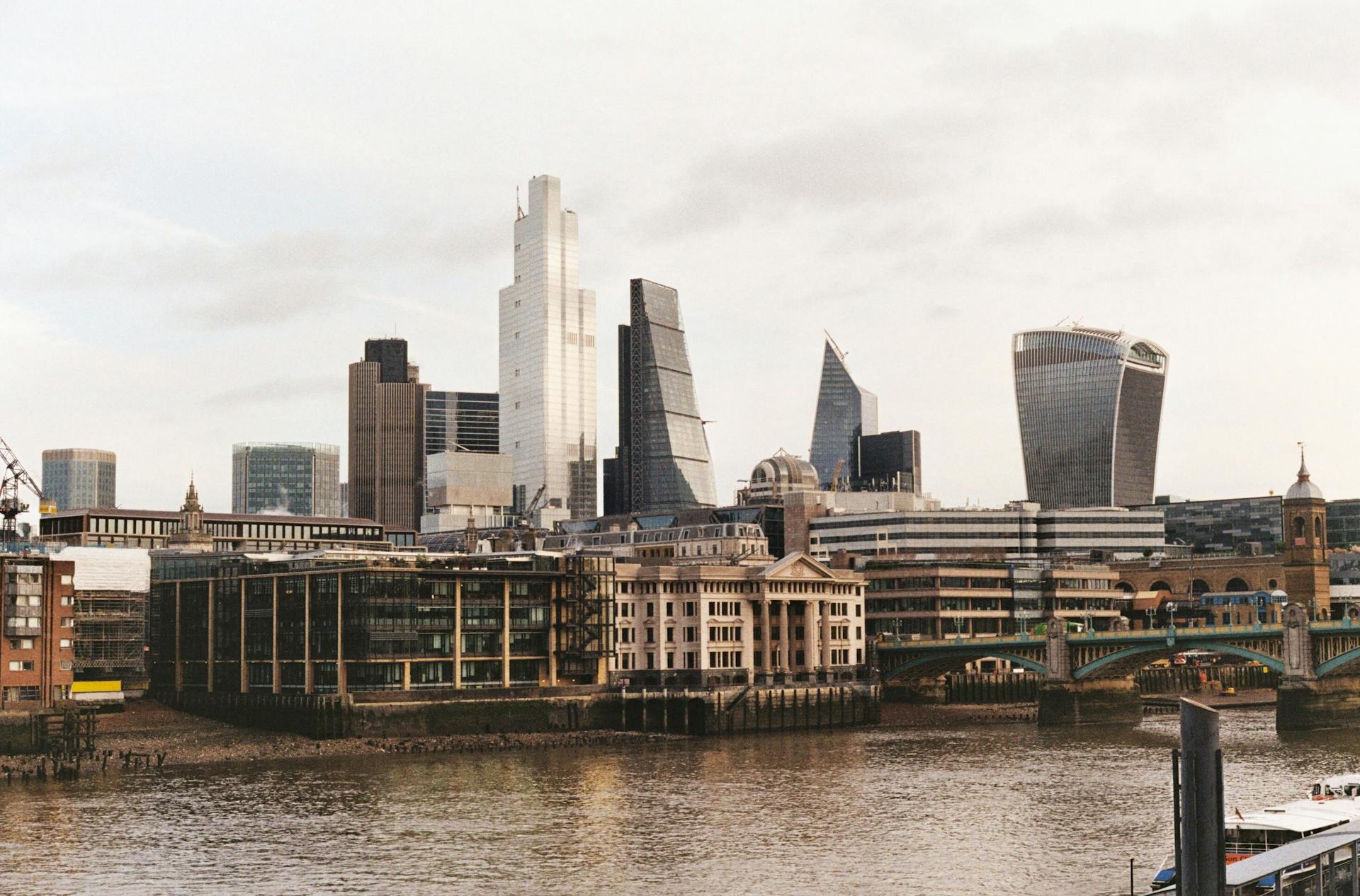 Modern skyline of London's financial district with skyscrapers and the Thames River.