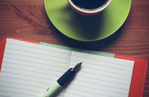 Free Fountain Pen on Top of Notebook Beside Drinking Mug Stock Photo