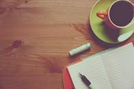 工作空间温馨而舒适，木桌上放着一杯咖啡、日记和笔