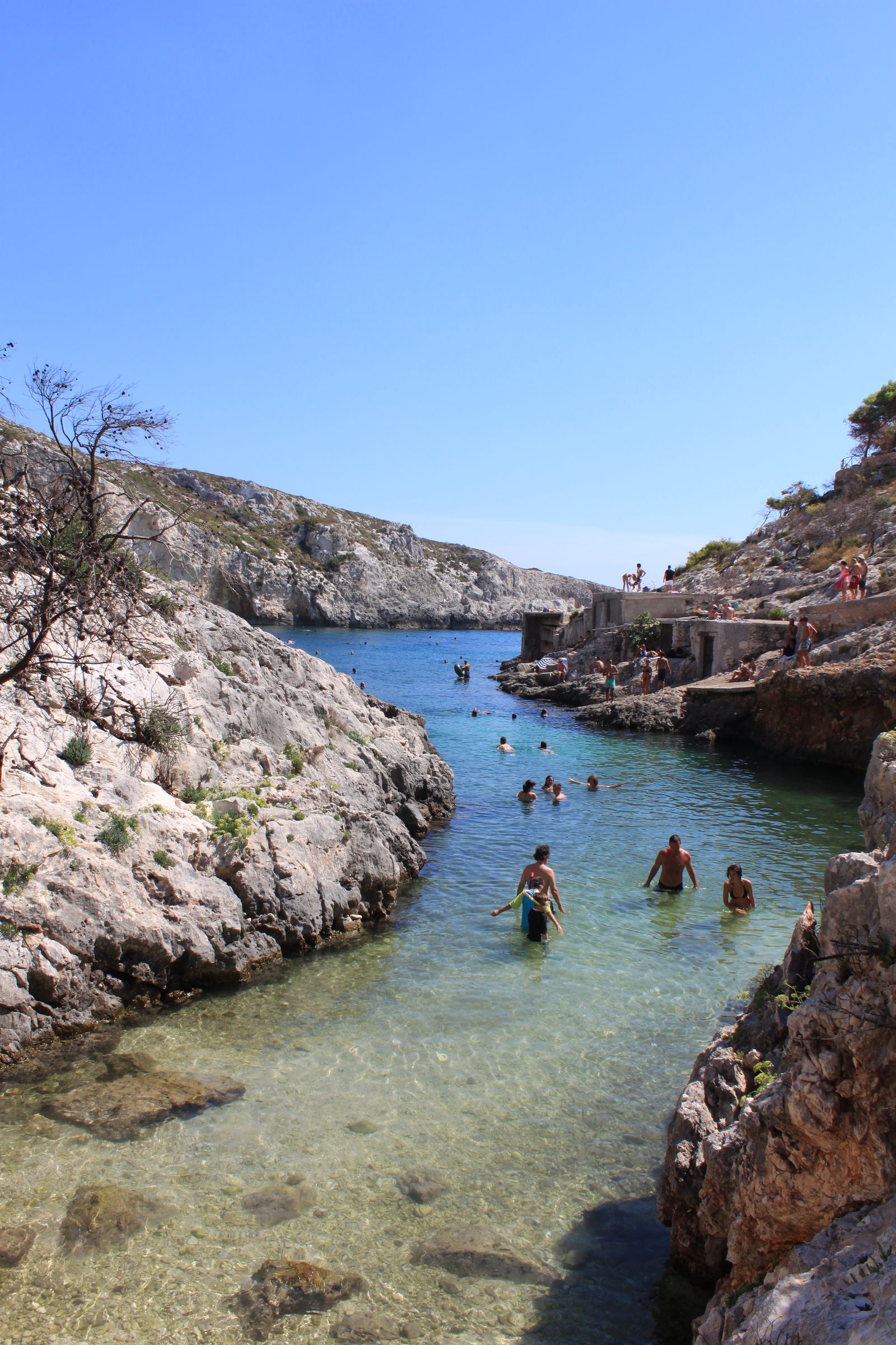 Swimmers enjoying a rocky cove with clear blue water
