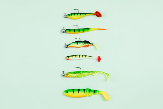 A selection of bright fishing lures laid out on a pastel green surface.