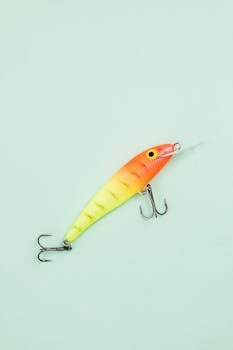 A vibrant fishing lure displayed against a pastel background in a flat lay style.