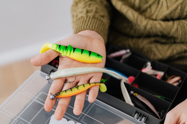 Assorted Fishing Lures On A Person's Hand