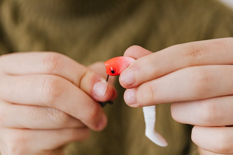 Hands Holding A White And Orange Fish Bait