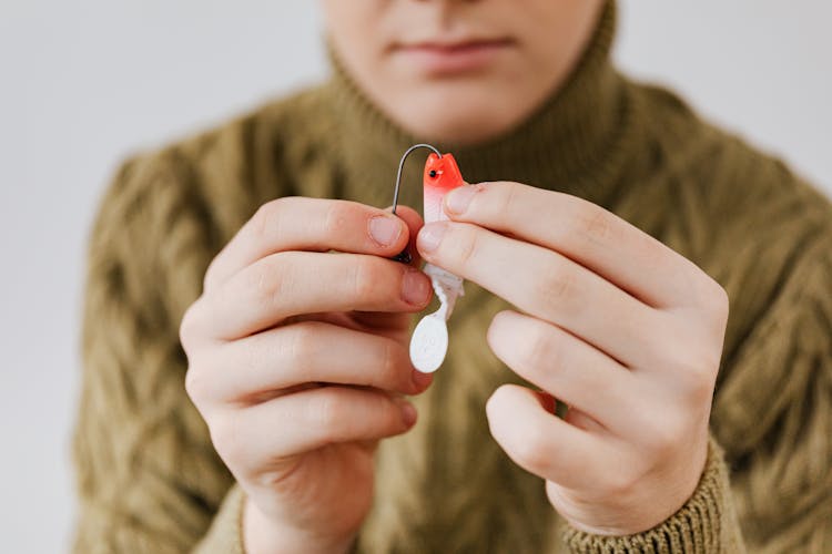 Person Holding A Hook And A Fishing Lure