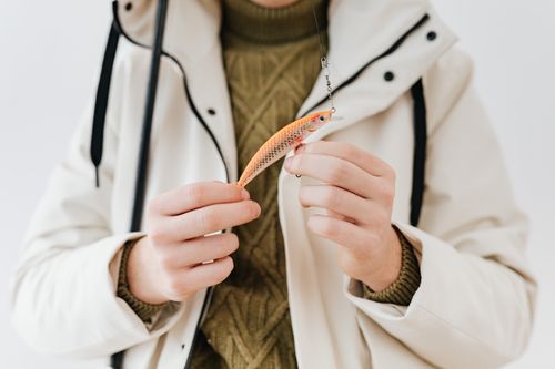 Free A person in a coat holding a colorful fishing lure close-up. Stock Photo