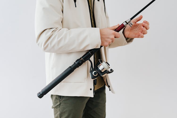 Person Wearing White Jacket Holding A Black Fishing Rod