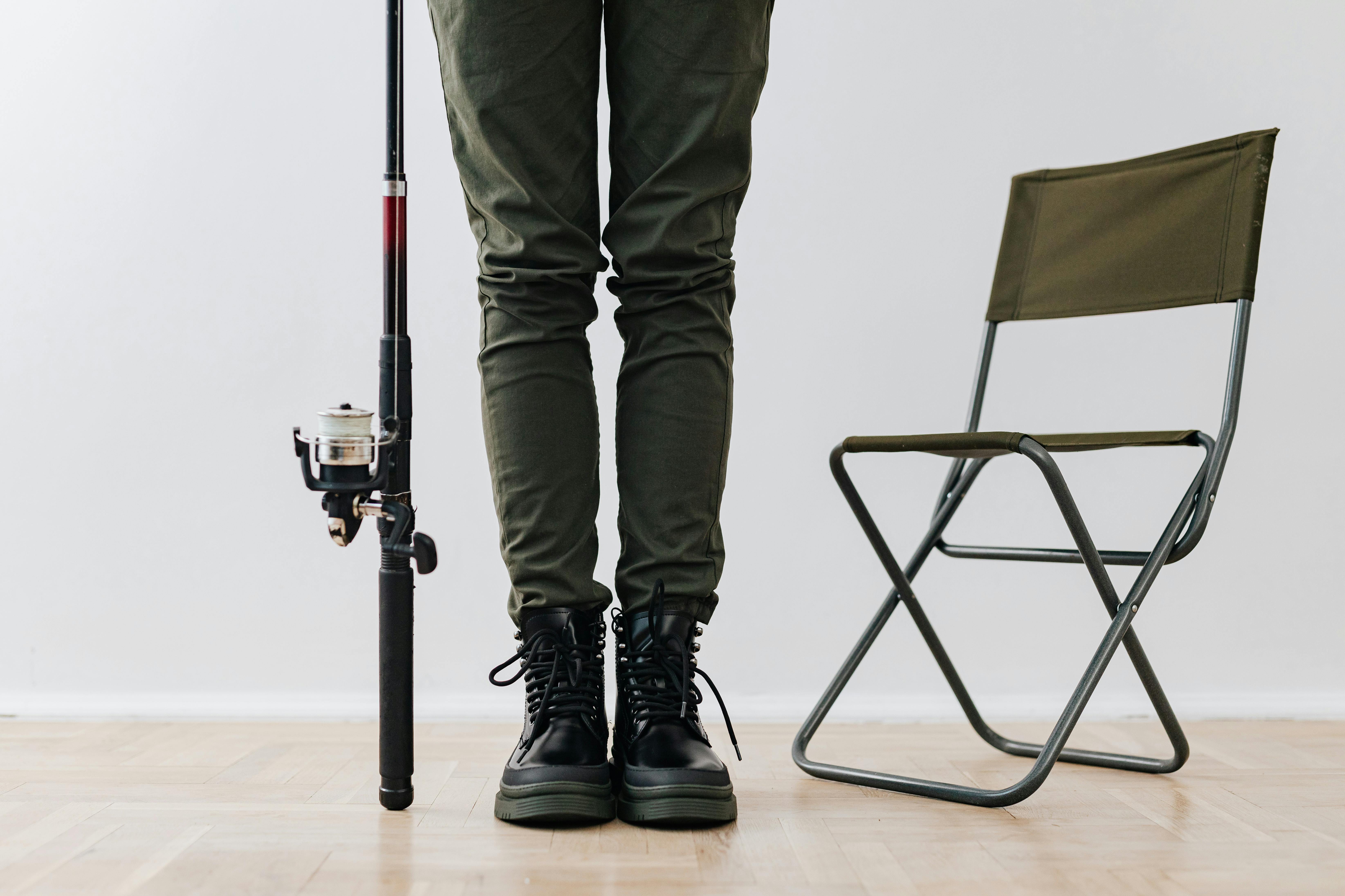 Close-up shot of person with fishing rod and folding chair indoors.