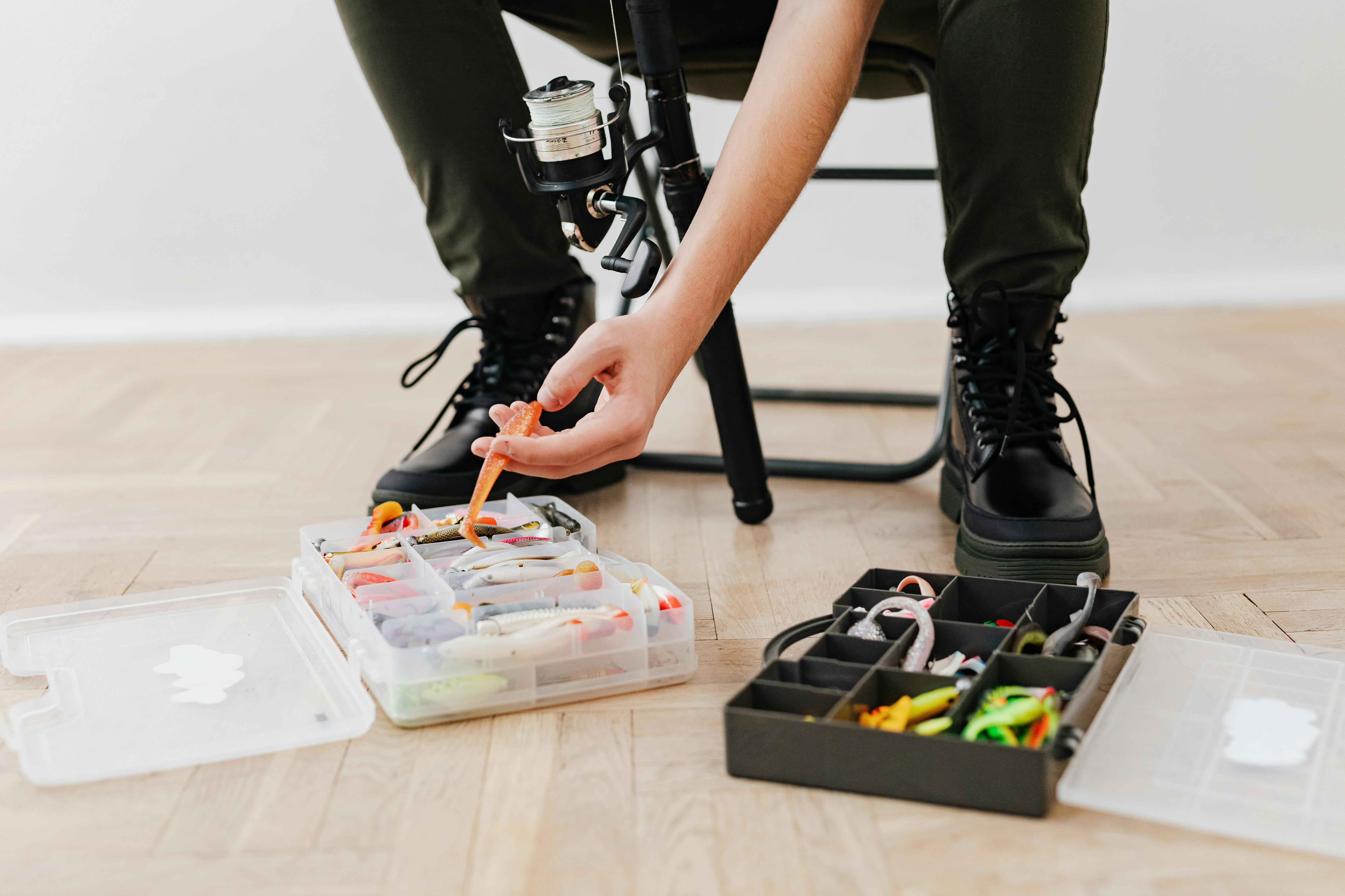 Close-up of a person organizing fishing lures and gear in a tackle box, ready for a fishing trip.