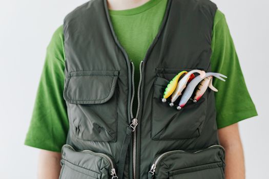 Close-up of person wearing a fishing vest with colorful baits displayed in the pocket.