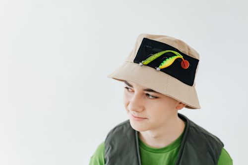 Free A young boy wearing a stylish fishing hat adorned with lures, showcasing modern outdoor fashion. Stock Photo