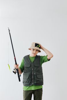 Teenage boy holding fishing rod and wearing a bucket hat, ready for a fishing adventure.