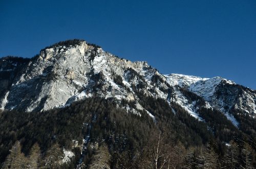 Free A breathtaking winter view of the Swiss Alps featuring snow-covered mountains under a clear blue sky. Stock Photo