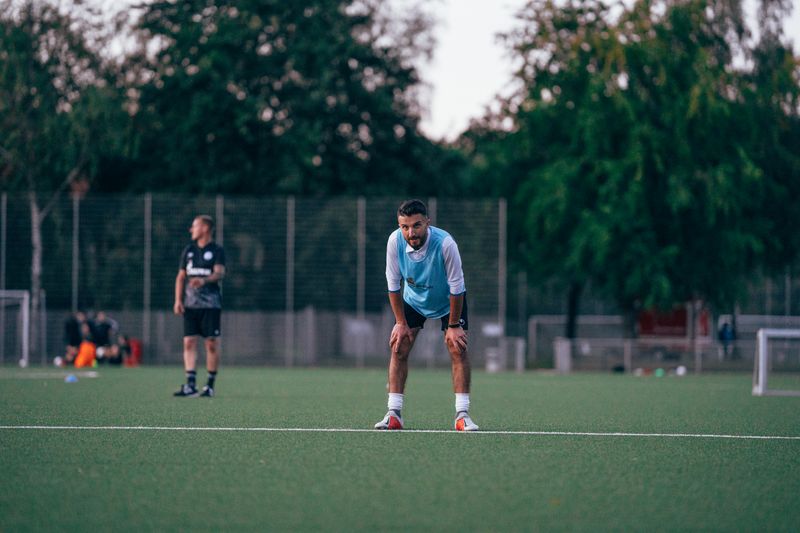Un jugador de fútbol con equipación apoyado en el suelo durante un entrenamiento