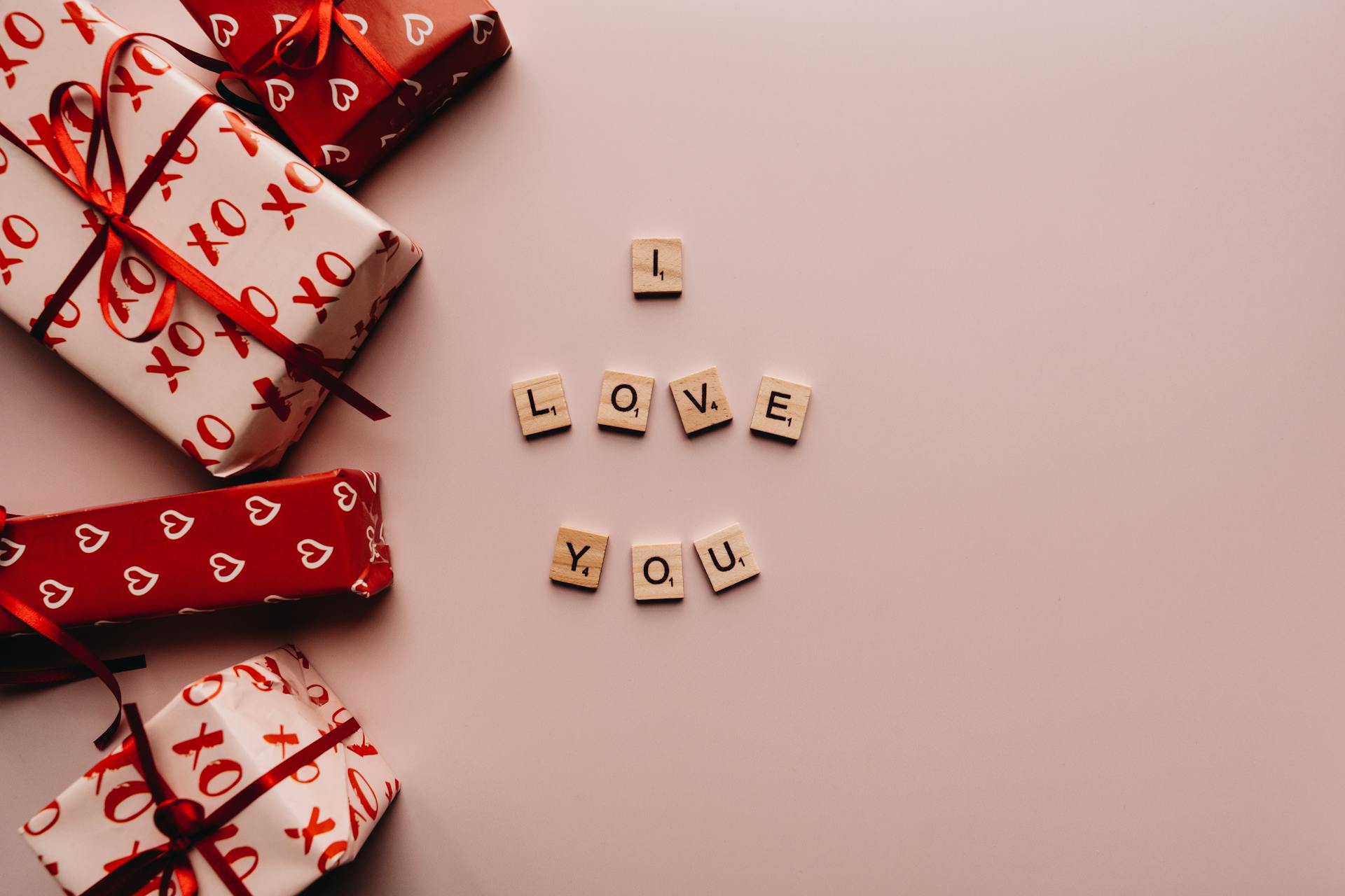 Creative romantic presentation with wrapped gifts and Scrabble tiles spelling 'I LOVE YOU' for romantic occasions.