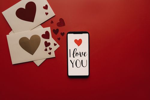 Free Smartphone with 'I Love You' display surrounded by red hearts and envelopes. Stock Photo