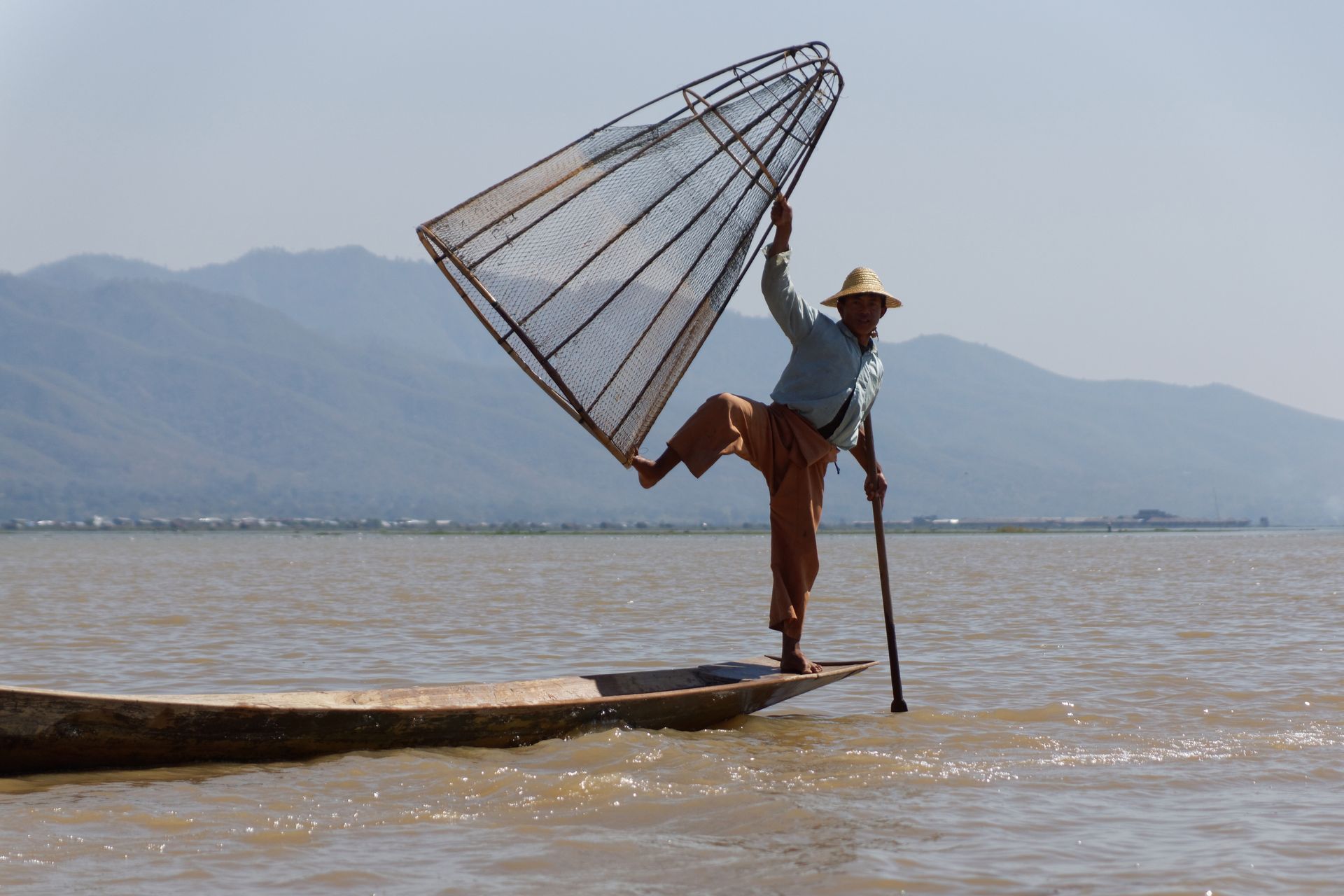 A fisherman balances on a canoe with a net on Inle Lake, Myanmar.