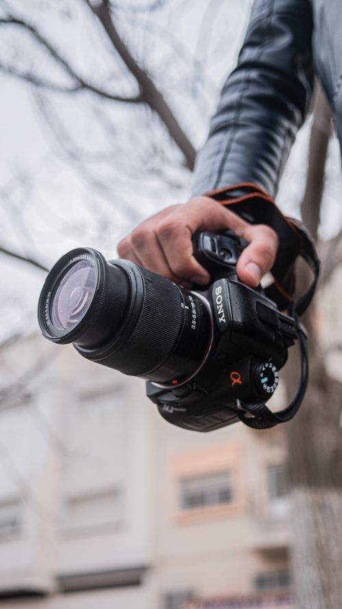 Free Detailed view of a person holding a DSLR camera outdoors, ideal for photography themes. Stock Photo