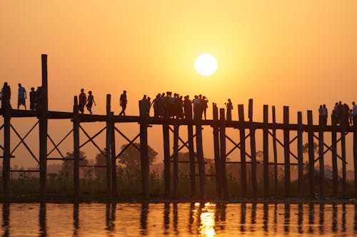 Silhouettes of People Standing on a Bridge During a Sunset