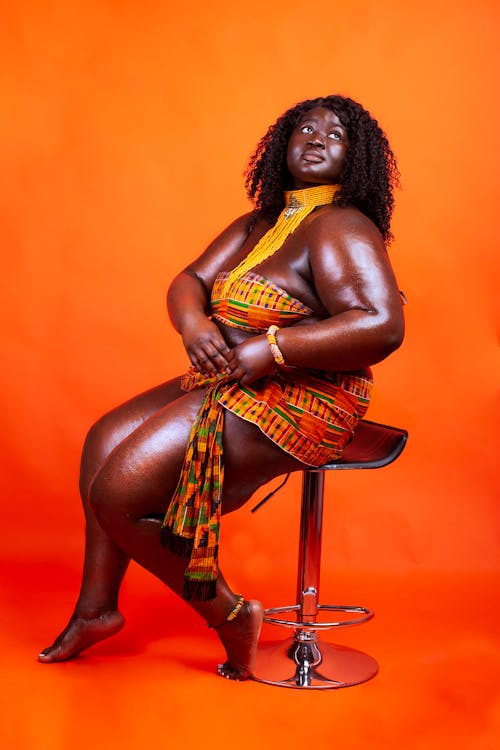 Woman in Yellow and Red Tube Top Sitting on Chair