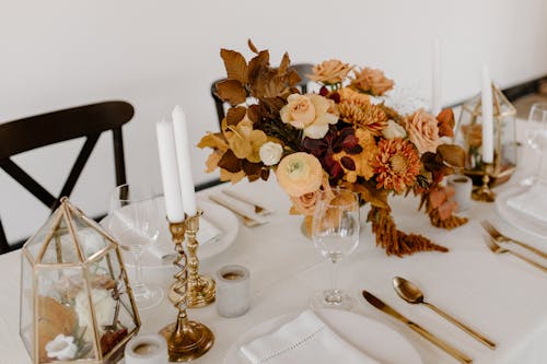 High angle of festive table decorated with bunches of blooming flowers placed near napkins candles and cutlery