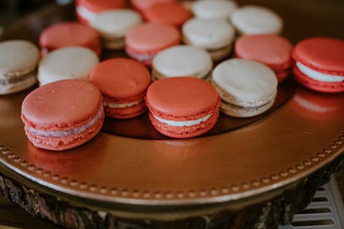 Free From above of colorful macaroons with cream placed on round stand for sweet treat Stock Photo